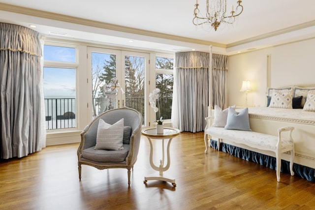 living area featuring crown molding, light wood-type flooring, a notable chandelier, and plenty of natural light