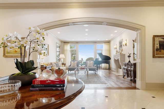 living area featuring light tile patterned floors, arched walkways, baseboards, ornamental molding, and recessed lighting