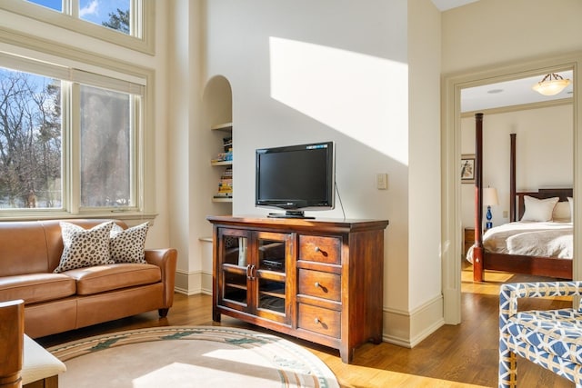 living room featuring a wealth of natural light, a towering ceiling, and wood finished floors