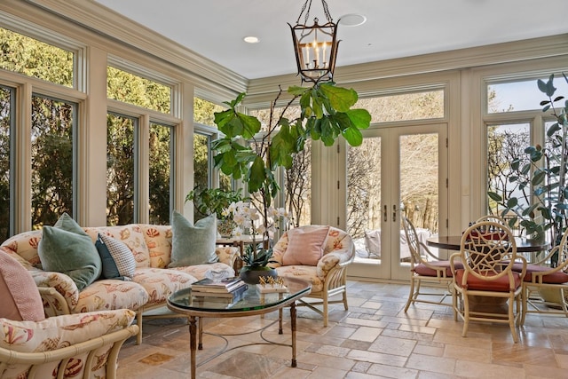 sunroom featuring french doors, a wealth of natural light, and a notable chandelier