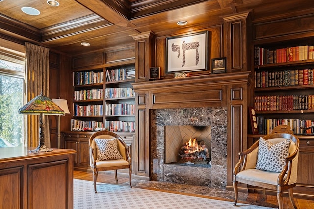 living area featuring built in shelves, a premium fireplace, ornamental molding, wooden ceiling, and coffered ceiling