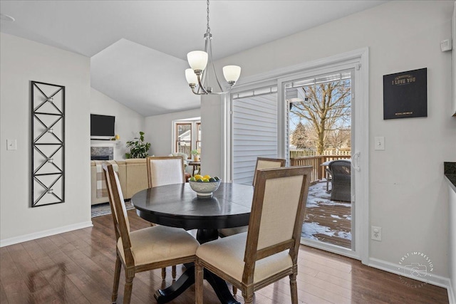 dining space with a notable chandelier, vaulted ceiling, dark hardwood / wood-style floors, and a healthy amount of sunlight