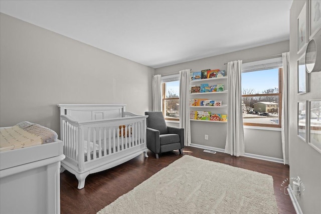 bedroom with a nursery area and dark wood-type flooring