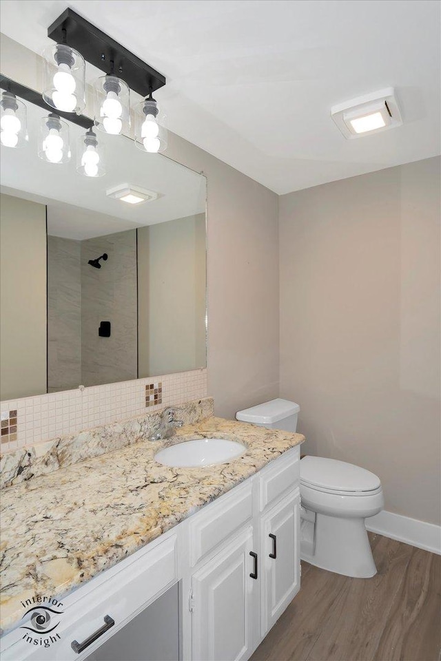 bathroom featuring backsplash, toilet, a tile shower, wood finished floors, and vanity