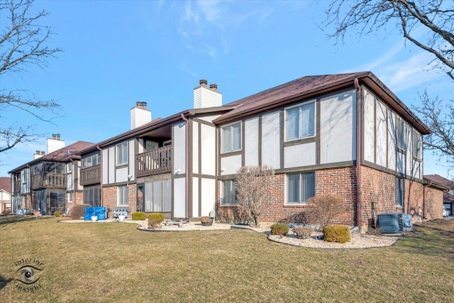 back of house featuring a yard, brick siding, central AC unit, and a chimney