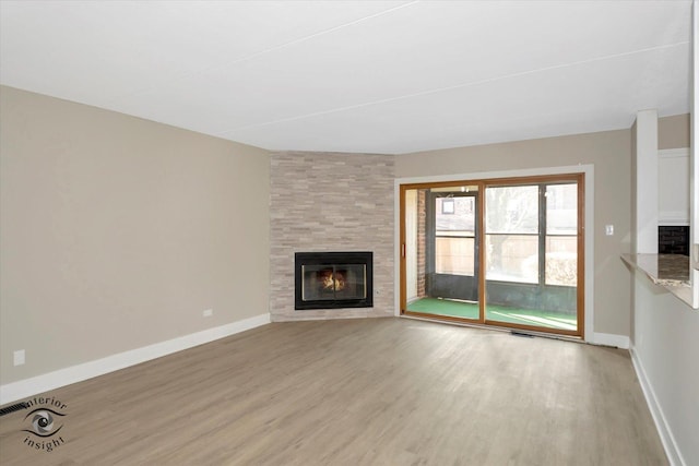 unfurnished living room featuring visible vents, a tile fireplace, baseboards, and wood finished floors