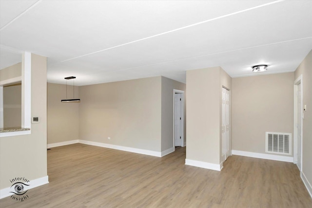 unfurnished room featuring wood finished floors, visible vents, and baseboards