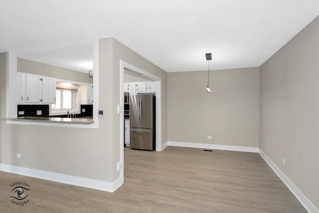 kitchen featuring tasteful backsplash, white cabinets, light wood-style flooring, and freestanding refrigerator