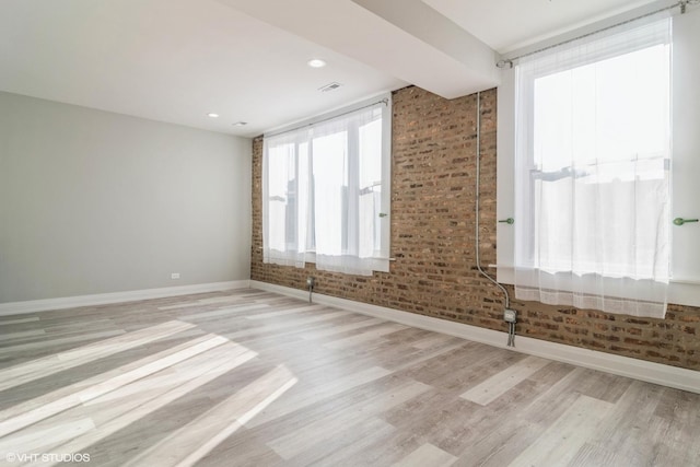 empty room featuring brick wall and light wood-type flooring