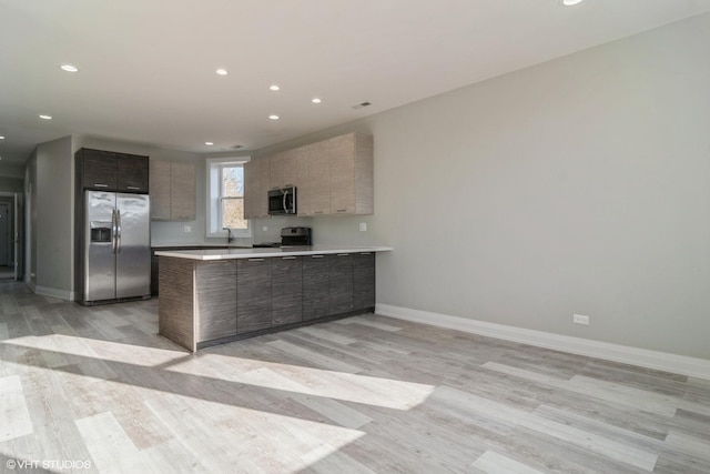 kitchen with stainless steel appliances, light hardwood / wood-style floors, and kitchen peninsula