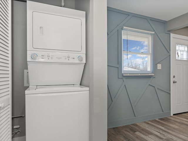 clothes washing area with stacked washer / dryer and hardwood / wood-style flooring