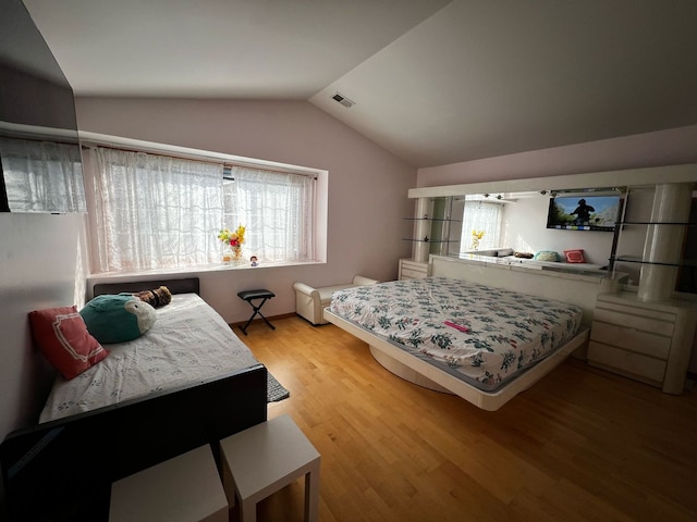 bedroom featuring lofted ceiling, light wood-type flooring, and visible vents