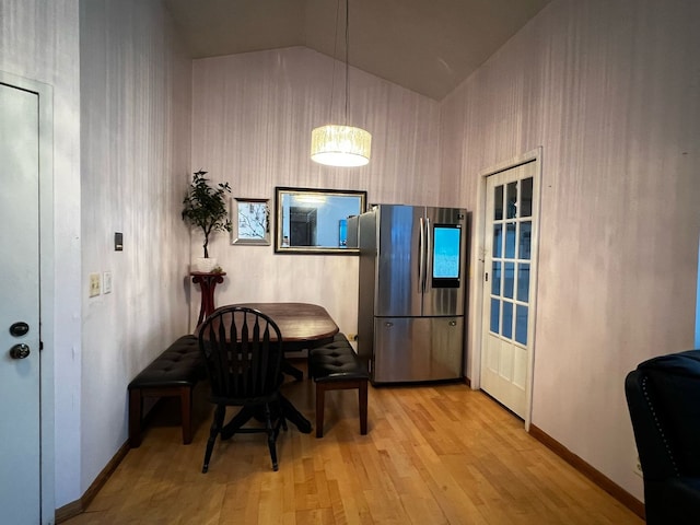 dining area with baseboards, vaulted ceiling, and light wood finished floors