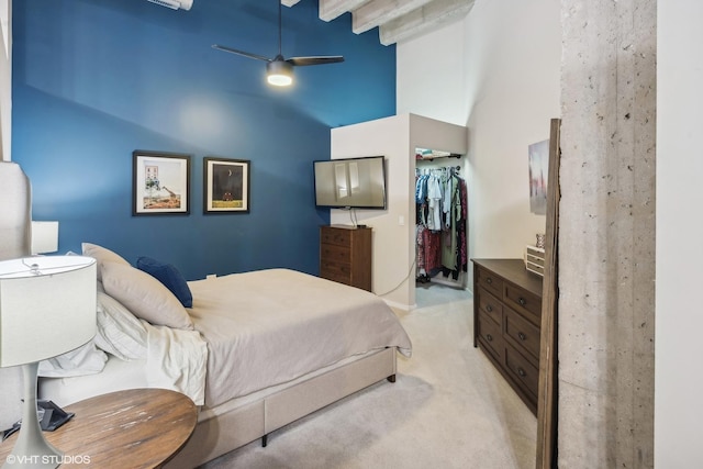 bedroom featuring a spacious closet, light carpet, a closet, a towering ceiling, and ceiling fan