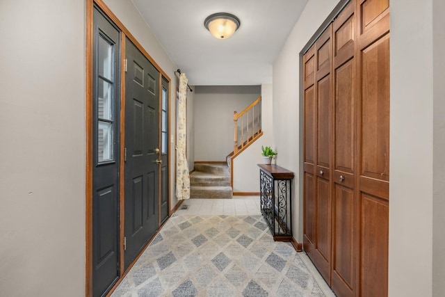 foyer with light carpet, baseboards, and stairway