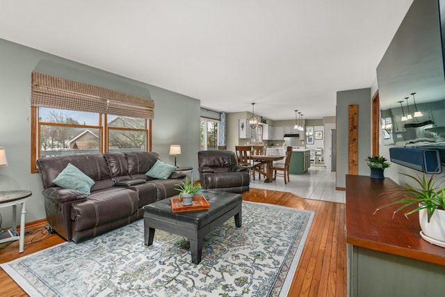 living room with light wood-style flooring, a chandelier, and baseboards