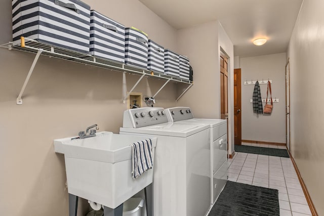 laundry area with laundry area, baseboards, washer and clothes dryer, a sink, and light tile patterned flooring