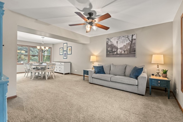 carpeted living area with baseboards and ceiling fan with notable chandelier