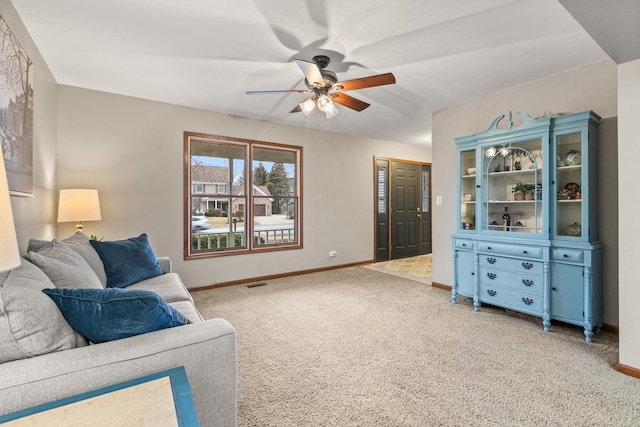 living area with light carpet, visible vents, baseboards, and ceiling fan