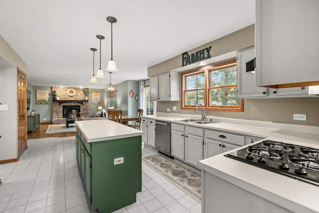 kitchen featuring a fireplace, black gas cooktop, green cabinets, a sink, and dishwasher