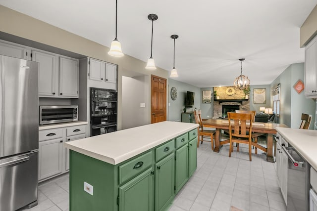 kitchen featuring light countertops, appliances with stainless steel finishes, a kitchen island, and green cabinetry