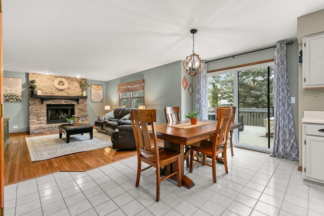 dining space featuring a wealth of natural light, a brick fireplace, and light tile patterned flooring