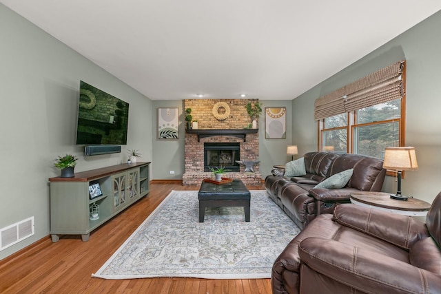 living room featuring visible vents, a fireplace, and wood finished floors