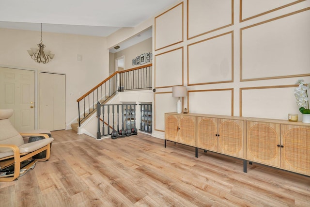 living area featuring a towering ceiling, a notable chandelier, and light hardwood / wood-style floors