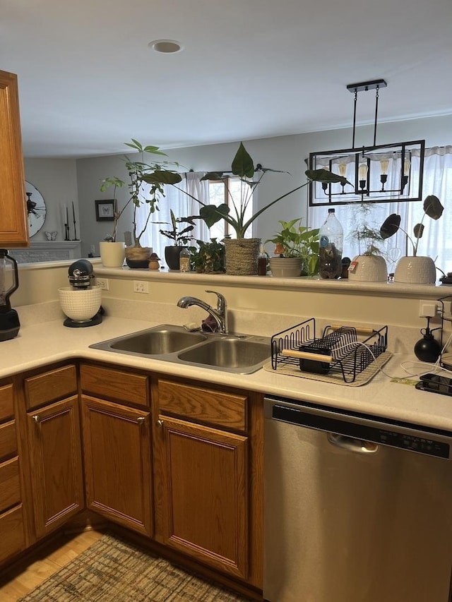 kitchen with sink, decorative light fixtures, stainless steel dishwasher, and light hardwood / wood-style floors