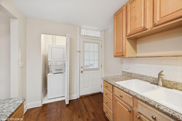 kitchen with dark hardwood / wood-style flooring, stacked washer and dryer, sink, backsplash, and light brown cabinetry