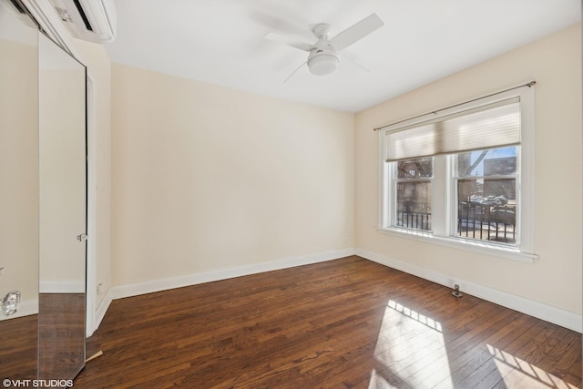 spare room featuring dark hardwood / wood-style flooring, ceiling fan, and a wall unit AC