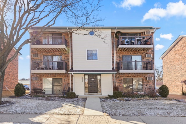 view of front of home featuring brick siding and a balcony