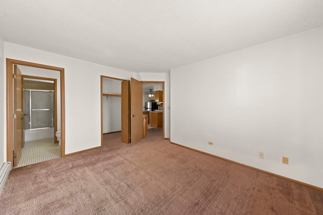 unfurnished bedroom featuring a baseboard heating unit, baseboards, light colored carpet, ensuite bathroom, and a closet