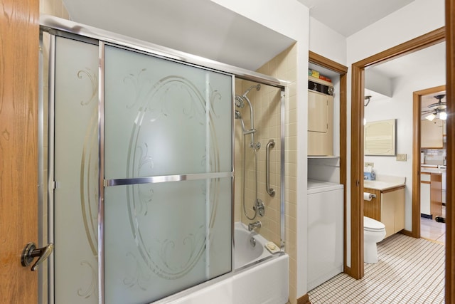 full bath featuring toilet, stacked washing maching and dryer, shower / bath combination with glass door, tile patterned flooring, and vanity