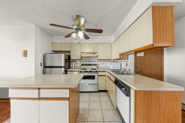 kitchen featuring under cabinet range hood, white appliances, light countertops, and a sink