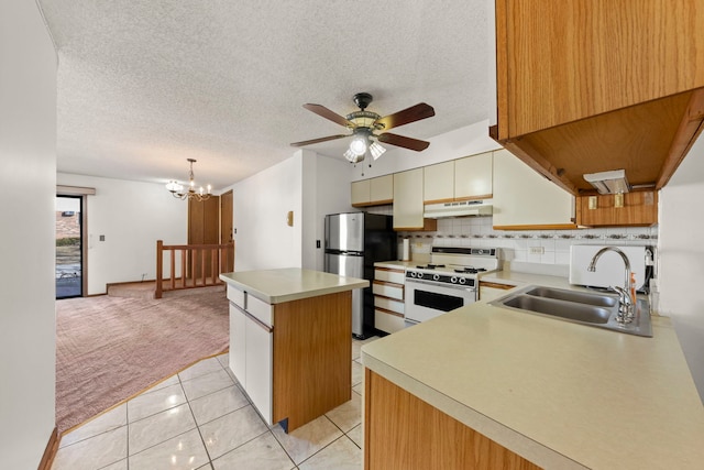 kitchen featuring freestanding refrigerator, a sink, white gas range oven, under cabinet range hood, and light colored carpet