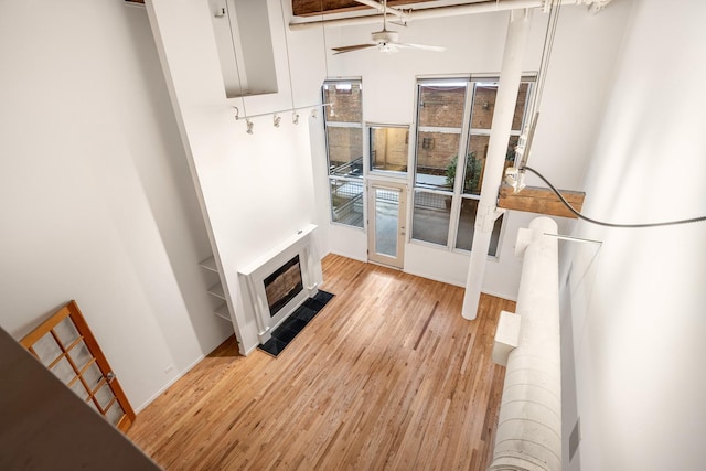 mudroom featuring light wood-style floors, a tile fireplace, heating unit, and a ceiling fan