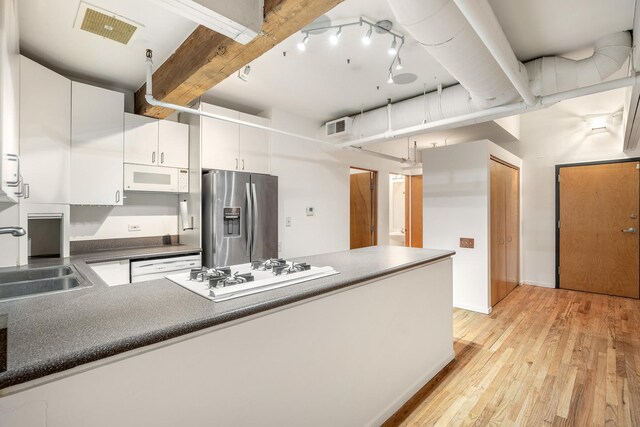 kitchen featuring white appliances, visible vents, white cabinets, dark countertops, and a sink