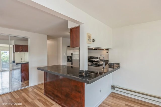 kitchen featuring stainless steel refrigerator with ice dispenser, kitchen peninsula, sink, and light wood-type flooring