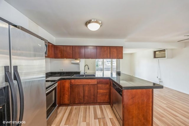 kitchen featuring sink, a wall mounted AC, appliances with stainless steel finishes, kitchen peninsula, and light hardwood / wood-style floors