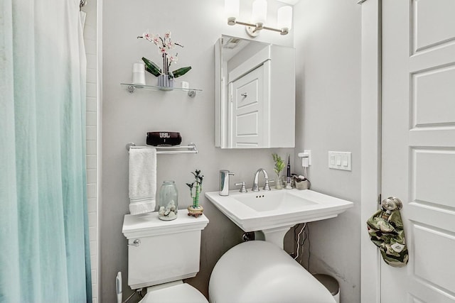 bathroom featuring curtained shower, a sink, and toilet