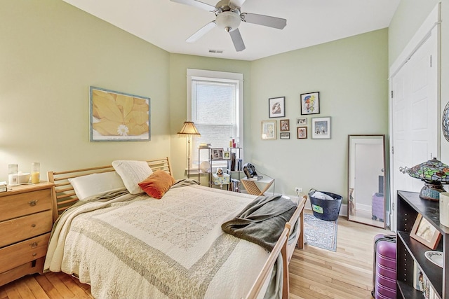 bedroom with light wood finished floors, visible vents, and a ceiling fan