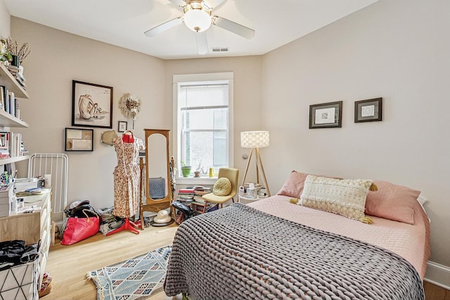 bedroom with a ceiling fan, visible vents, and wood finished floors