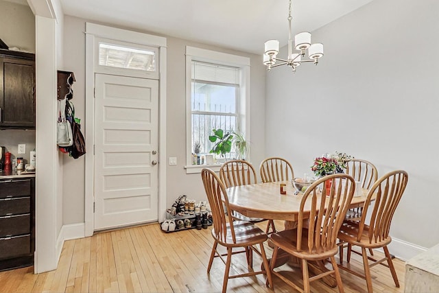 dining room featuring light wood-style flooring, baseboards, and a notable chandelier