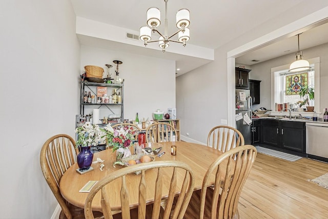 dining space with a chandelier, light wood-type flooring, visible vents, and baseboards