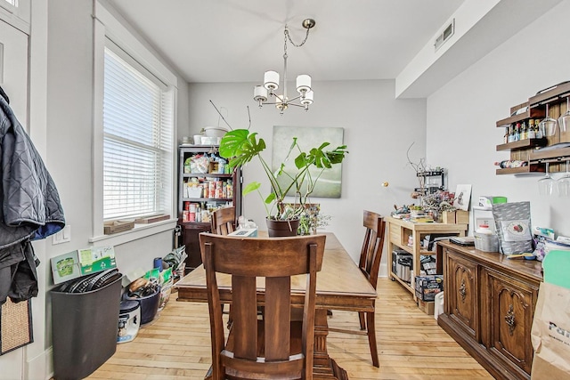 dining space featuring light wood-style flooring, visible vents, and a notable chandelier