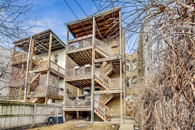 rear view of property featuring stairs and fence