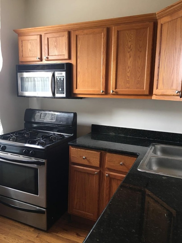 kitchen with wood-type flooring, sink, and stainless steel range with gas stovetop