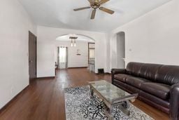 living area featuring a ceiling fan, arched walkways, and dark wood finished floors