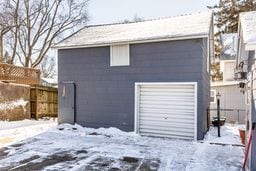 snow covered garage with a garage and fence